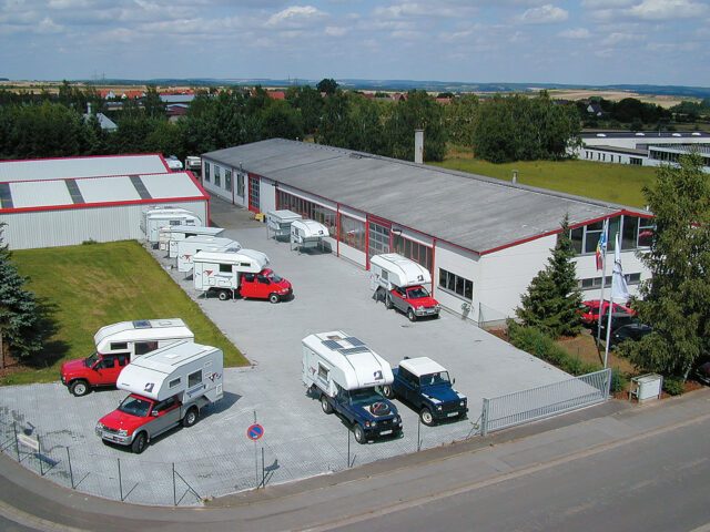 Luftaufnahme des Tischer Werksgeländes – mehrere Wohnkabinen und Fahrzeuge auf dem Hof.