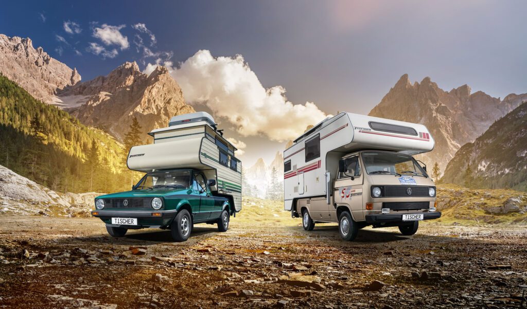 Zwei klassische Tischer-Kabinen auf Pick-ups, geparkt vor einer alpinen Bergkulisse.