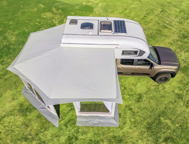 Draufsicht: Tischer Vorzelt mit geöffneten Seiten, montiert an Kabine mit Solarpanel.