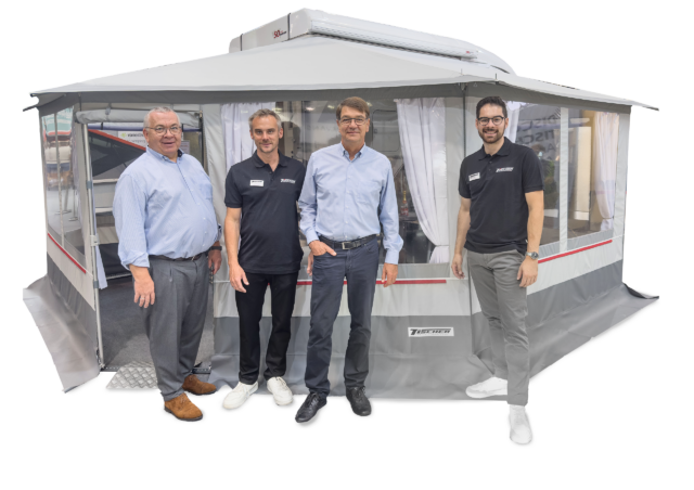 Tischer Team mit aufgebautem Vorzelt bei Präsentation, vier Personen posieren vor dem Produkt.